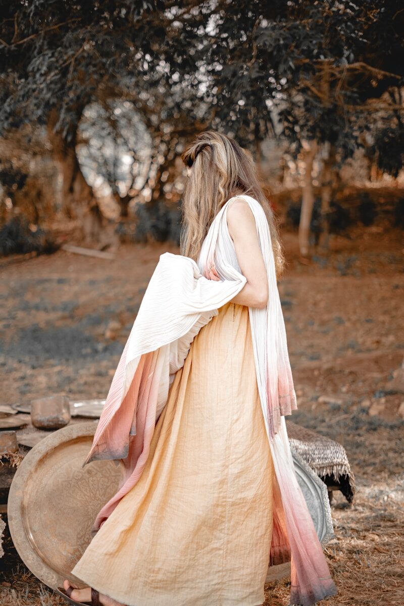 من نحن a woman in a long dress standing in a field