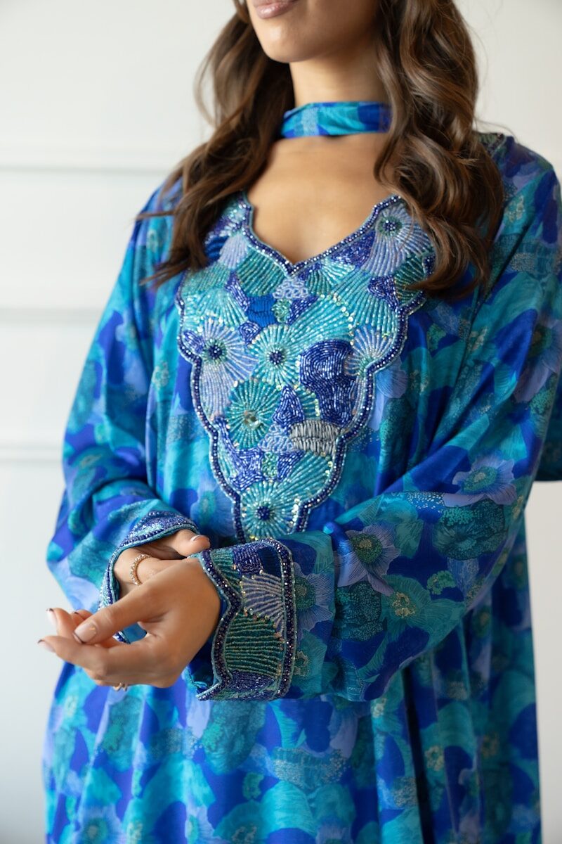 Woman wearing a blue patterned kaftan with beaded neckline.