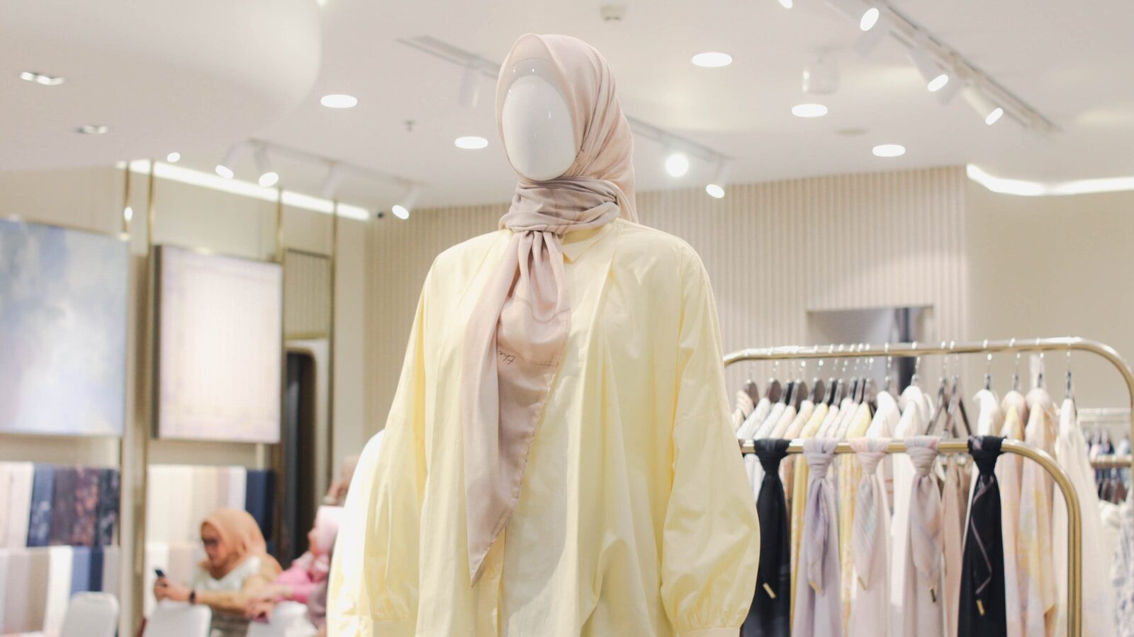 بيت Mannequin wearing a light yellow dress and hijab.