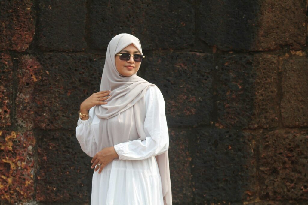 Why High-Quality Linen Is the Perfect Fabric for Summer? Woman in a hijab and sunglasses stands by stone wall